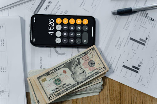 Cash Money and a Calculator on White Paper