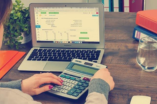 bookkeeper duties and responsibilities for small businesses using a calculator and laptop