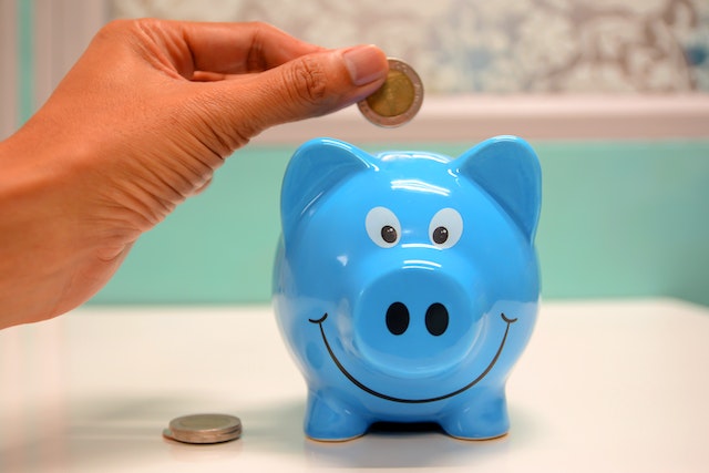Person putting coins in a blue piggybank for law firm KPI