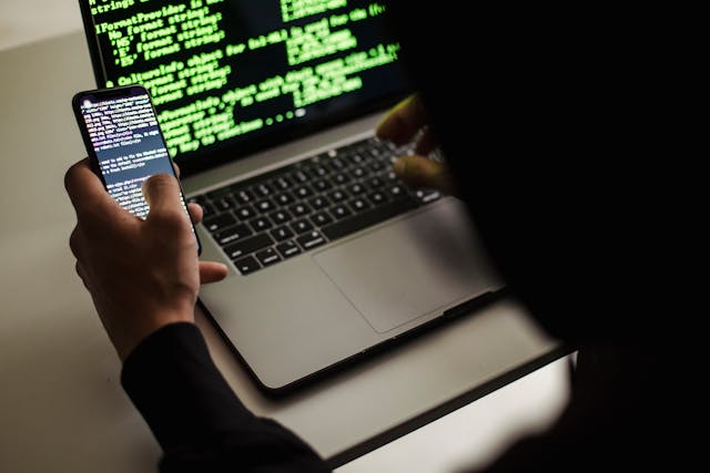 Person looking at phone and laptop